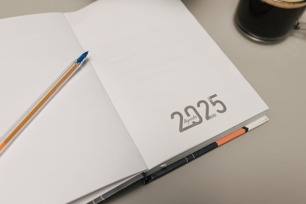Open 2025 planner with a pen and coffee cup on a desk, ideal for productivity themes.