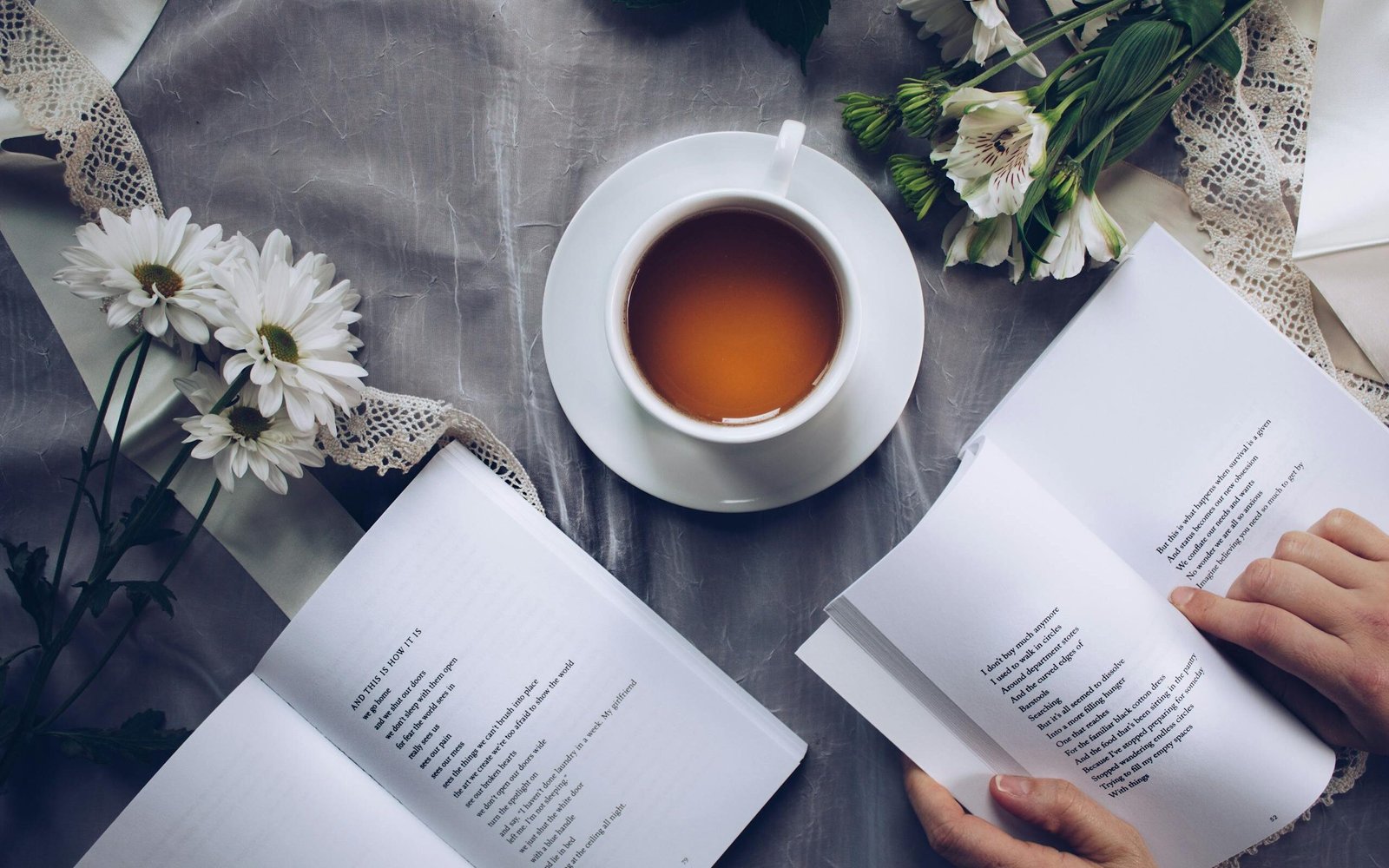 White Ceramic Teacup With Saucer Near Two Books Above Gray Floral Textile